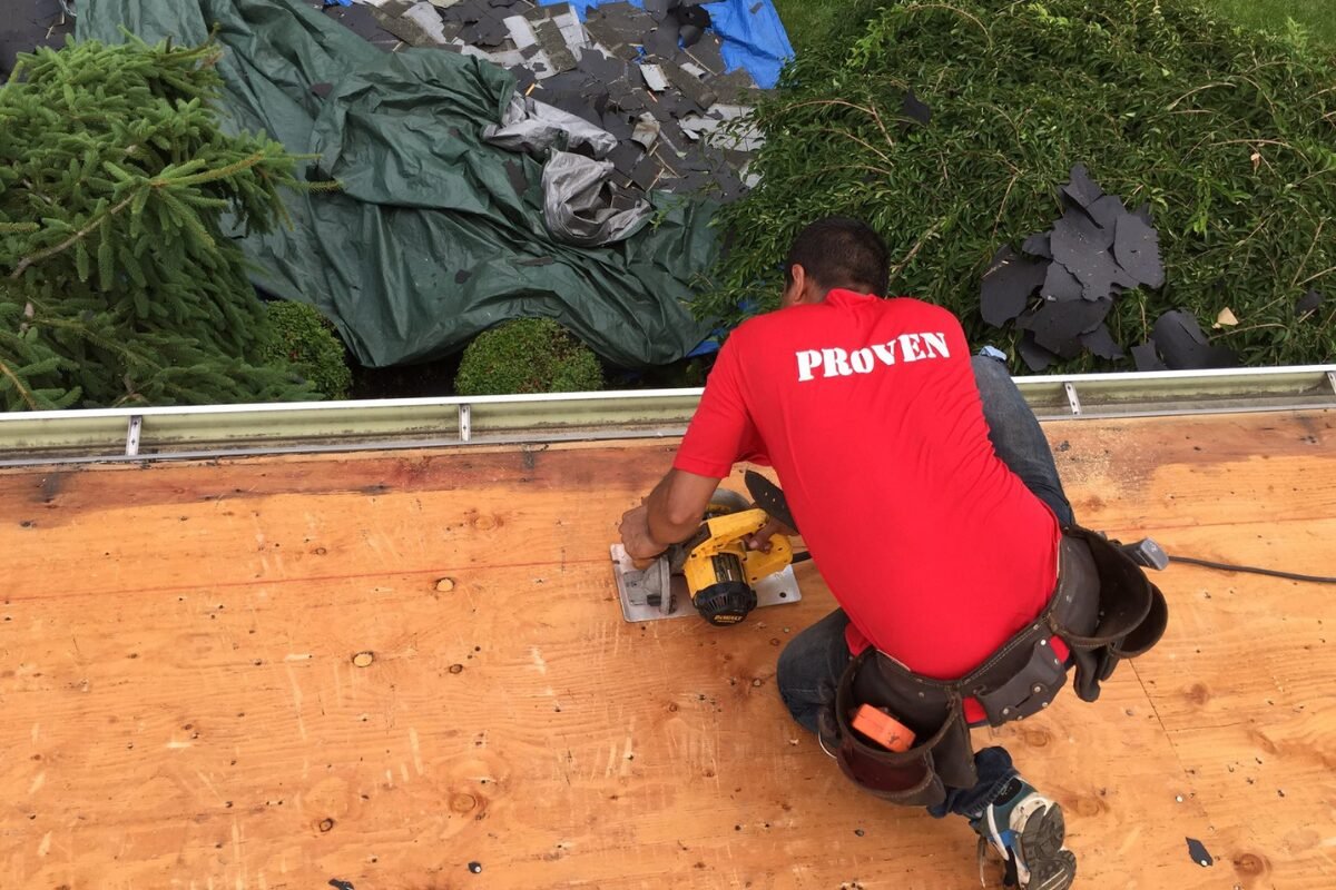 Roof contractor in a red shirt actively engaged in performing a roof repair in Monmouth County NJ, embodying professionalism and expertise in the field.