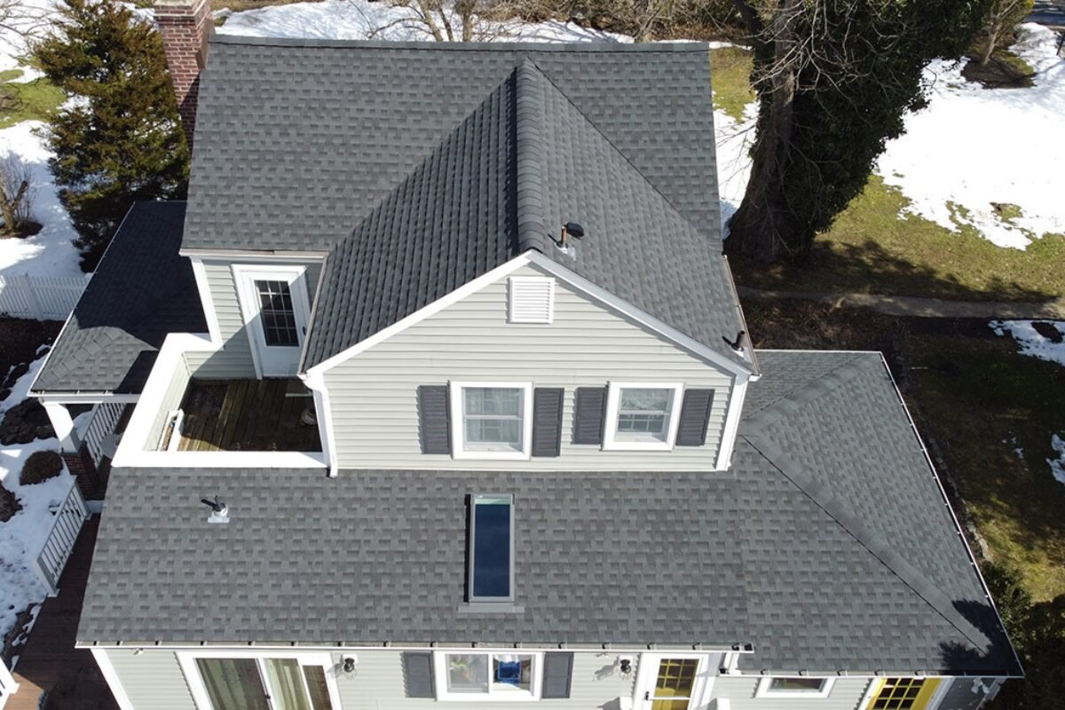 Aerial view of a newly replaced multi-level shingle roof with a skylight in Monmouth County, NJ, showcasing our proficiency in enhancing homes with complex roofing solutions.