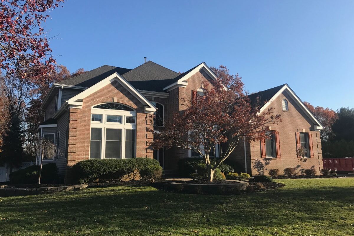 New black shingle roof on a large, beautiful brick home in Monmouth County, NJ, highlighting our expertise in roof replacement that enhances both beauty and durability.