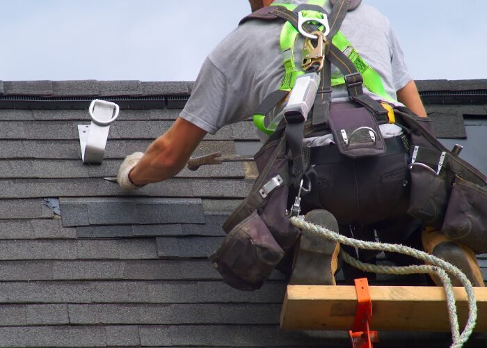 Roofer in Monmouth County NJ expertly repairing a damaged roof, highlighting skillful precision in roof restoration.